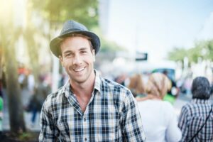 A young man wearing a fedora in a park.
