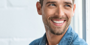 A young man smiling with porcelain veneers to repair chipped teeth in Casper.