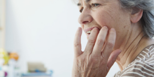 A woman clutching her mouth in pain from untreated gum disease.