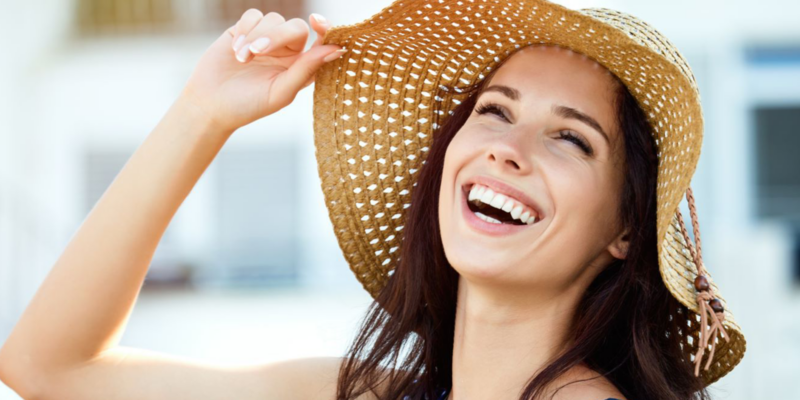 A young woman smiling while wearing a sunhat on vacation after teeth whitening in Casper.