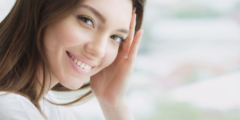 A young woman smiling with professionally whitened teeth.