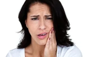 A woman clutching her jaw in pain from untreated TMJ disorder in Casper.